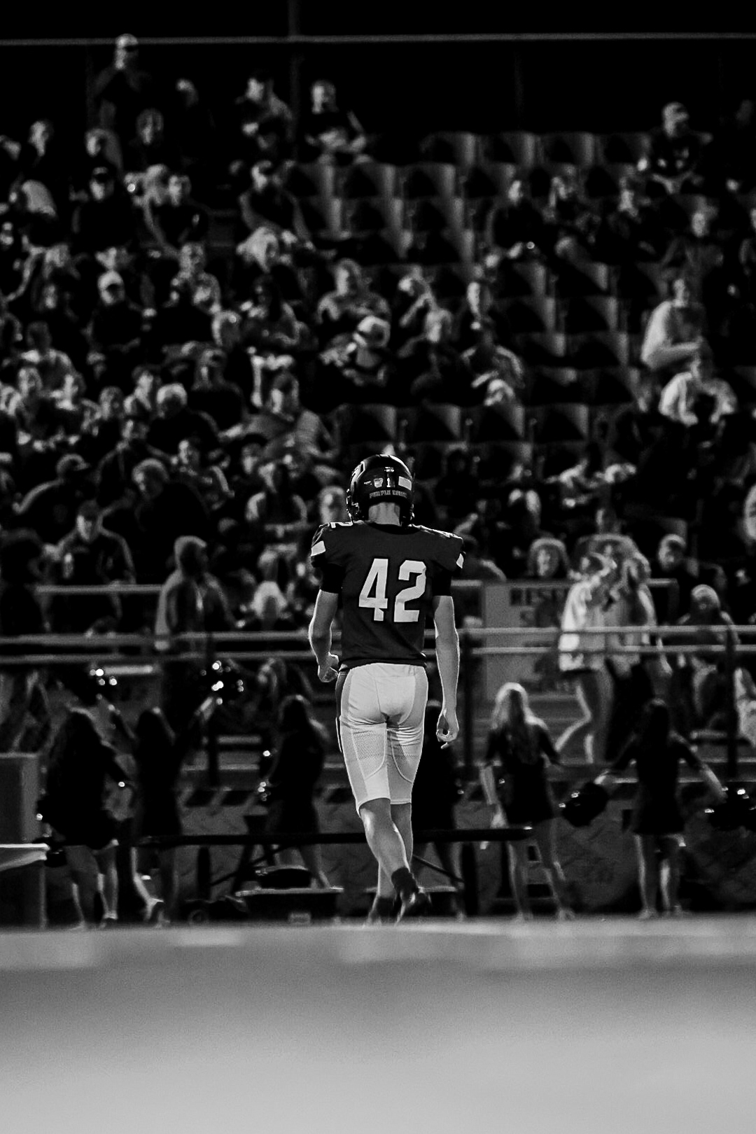 Black-and-white rear view of Ethan Farthing walking the field in uniform number 42 with the crowd in the background.
